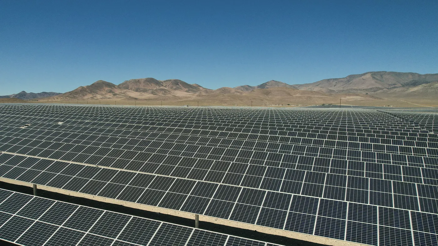 Rows of solar panels across a desert plain.