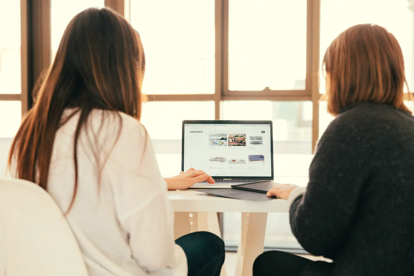 Two people discuss a brief at a laptop.